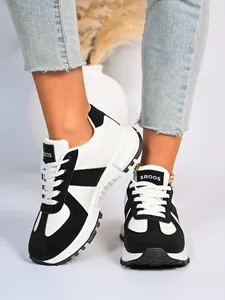 Primo piano di sneaker casual da donna bicolore bianco e nero indossate con jeans.