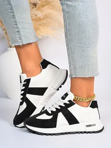 Dettaglio ravvicinato di sneaker da donna bianche e nere stile GAT indossate ai piedi.