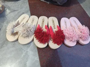 Primer plano de chanclas de plataforma con grandes flores de flecos en varios colores