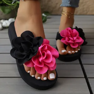 Primer plano de chanclas de plataforma negras con grandes flores de tela rosa y negro