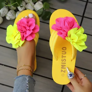 Primer plano de chanclas de plataforma amarillas con grandes flores de tela rosa y amarilla.