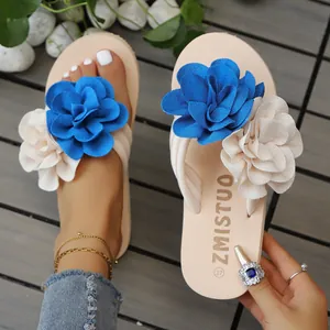 Primer plano de chanclas de plataforma beige con flores de tela azules y cremas
