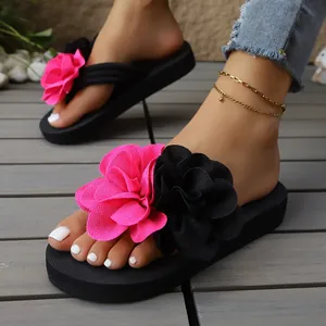 Detalle de chanclas de plataforma para mujer con grandes flores de tela rosas y negras
