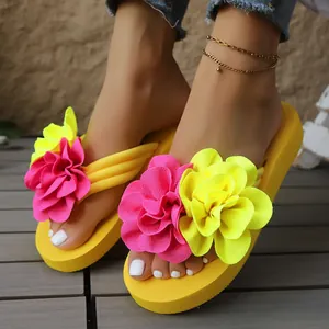 Primer plano de chanclas amarillas con grandes flores de tela rosa y amarilla decorativas.
