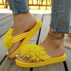 Chanclas amarillas de plataforma con borla de flores puestas