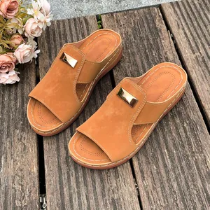 Détail de sandales compensées marron avec boucles dorées sur un plateau en bois rustique