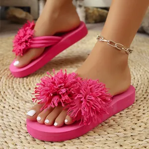 Vista detallada de las chanclas rosa con plataforma y pompones sobre una alfombra tejida