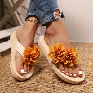 Detalle de chanclas con plataforma para mujer con grandes flores de tela naranja vibrante