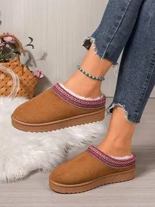 Detailed view of cozy brown suede slippers with soft white fleece lining on a model