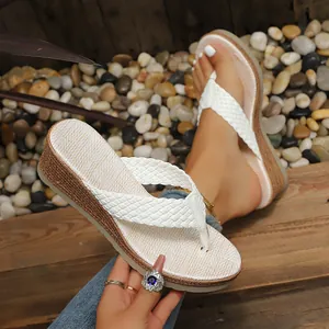 Dettaglio di infradito con zeppa bianche intrecciate e spessa suola platform estiva