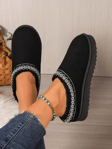 Close-up of stylish black suede slippers with white embroidery and cozy fur lining