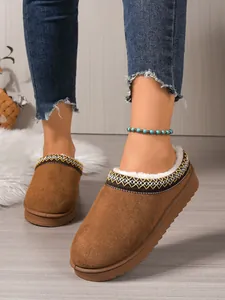 Detailed view of brown suede slippers featuring white faux fur lining and ethnic embroidery