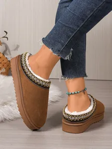 Detail view of brown suede winter clogs with plush white faux fur lining and embroidery