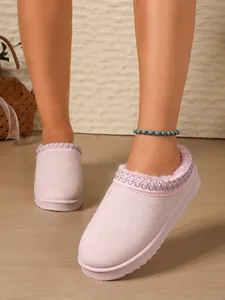 Close-up view of pink fuzzy suede slippers featuring embroidered trim and soft comfort sole