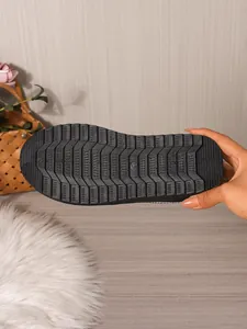 Detailed view of the non-slip textured rubber sole of black winter mule slippers.