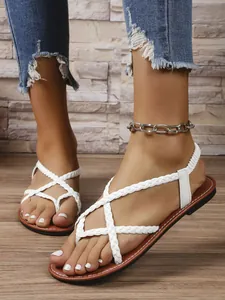 Détail de sandales plates tressées blanches pour femmes avec semelle marron, style décontracté.
