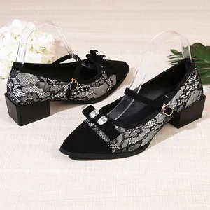 Close-up detail of black lace pointed toe pumps with crystal bow and Mary Jane strap