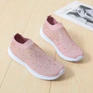 Detailansicht der pinkfarbenen Strick-Sneaker mit Strasssteinen auf Holzboden