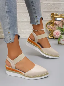 Detail of beige closed toe wedge sandals with braided rope platform and elastic strap.