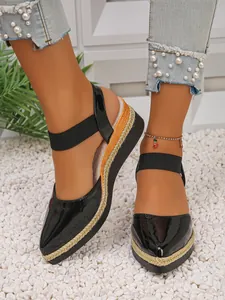 Close-up detail of black patent leather wedge sandals with braided rope sole design.