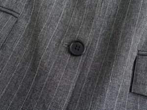 Detailansicht von schwarzem Knopf und grauem Nadelstreifenstoff bei einem Damen-Blazer