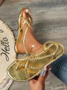 Gros plan de sandales plates tressées dorées pour femmes avec un design de plage à entre-doigt