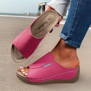 Elegantes sandalias de cuña rosas con punta abierta para mujer en una playa