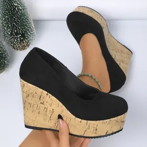 Vista lateral detallada de elegantes zapatos de cuña negros con plataforma de corcho
