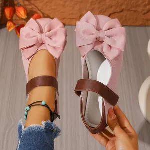 Primer plano de zapatos Mary Jane rosas con lazos grandes y correas de velcro marrón.