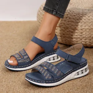 Detalle de sandalias de cuña azules con pedrería y suela transparente de colchón de aire.