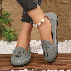 Detailed close-up of gray women's flat loafers featuring elegant tassel and moccasin stitching