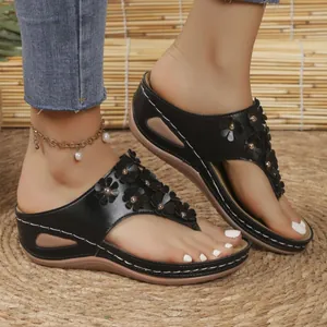 Eleganti sandali neri con zeppa caratterizzati da fiori 3D decorativi e borchie metalliche.