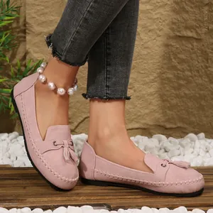 Close-up of stylish pink suede loafers with tassel details worn on a lifestyle model