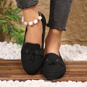Close-up view of black women's slip-on loafers with tassel detail and a pearl anklet