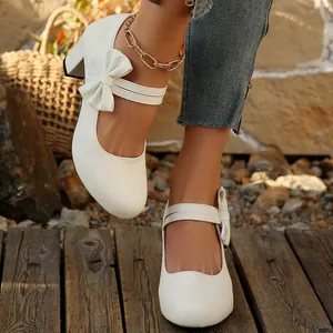 Detalle de zapatos Mary Jane blancos con tacón ancho y un elegante lazo decorativo
