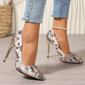 Detailweergave van damesstiletto's met etnische print en gouden naaldhakken nu.