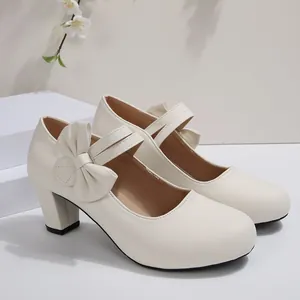 Vista detallada de zapatos crema de tacón grueso con lazo grande y correas Mary Jane