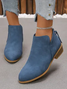 Macro detail view of blue suede-like pointed toe ankle boots featuring a low block heel
