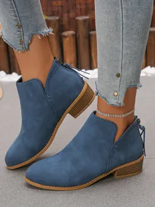 Stylish blue faux suede ankle boots with side cutout and chunky block heel on feet