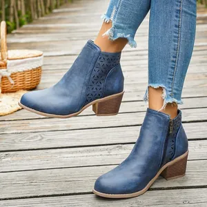 Elegante blauwe enkellaarsjes met gatenpatroon en blokhak op een rustiek houten pad.