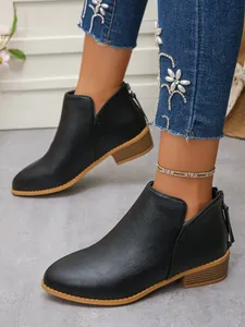 Detailed side view showing black pointed toe ankle boots with a chunky low heel