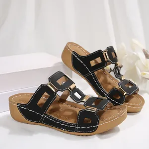 Detail van zwarte dames wedge sandalen met gouden gesp en uitgesneden bandjes