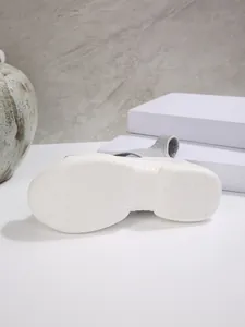 Close-up van de antislip witte plateauzool van een grijze gebreide sportsandaal