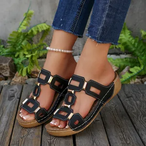 Modieuze zwarte sleehak sandalen met gouden gespen en witte stiksels op houten dek