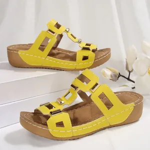 Zijaanzicht van gele sleehaksandalen met gouden studs en opengewerkte bandjes