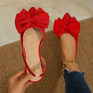 Close-up of elegant red pointed-toe flat shoes with large decorative bows and slingback.