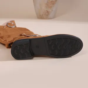 Detailed macro view of the non-slip rubber sole on brown slouchy suede mid-calf boots
