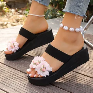 Detail von rosa 3D-Blumendekorationen auf schwarzen Keilabsatz-Sandalen für den Sommer.