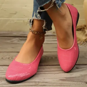 Eleganti ballerine rosa con motivo a coccodrillo indossate su un ponte di legno.