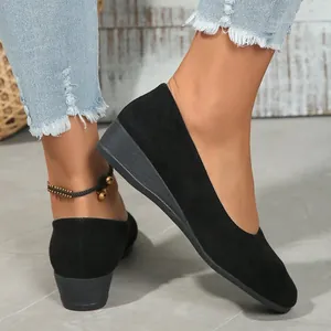 Detail view of elegant black suede wedge shoes worn with stylish frayed denim jeans
